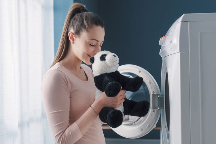 Ilustrasi mencuci boneka dengan mesin cuci.