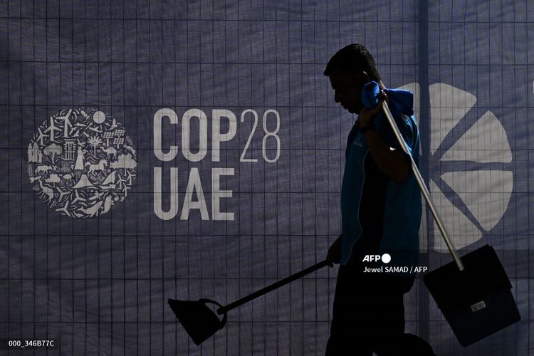 Seorang pekerja berjalan melewati logo COP28 menjelang KTT iklim PBB tersebut di Dubai, Uni Emirat Arab (UEA), Selasa (28/11/2023). Sekjen PBB mendesak para pemimpin dunia untuk mengambil tindakan tegas guna mengatasi perubahan iklim yang semakin memburuk ketika mereka berkumpul di KTT COP28 mulai Kamis (30/11/2023).