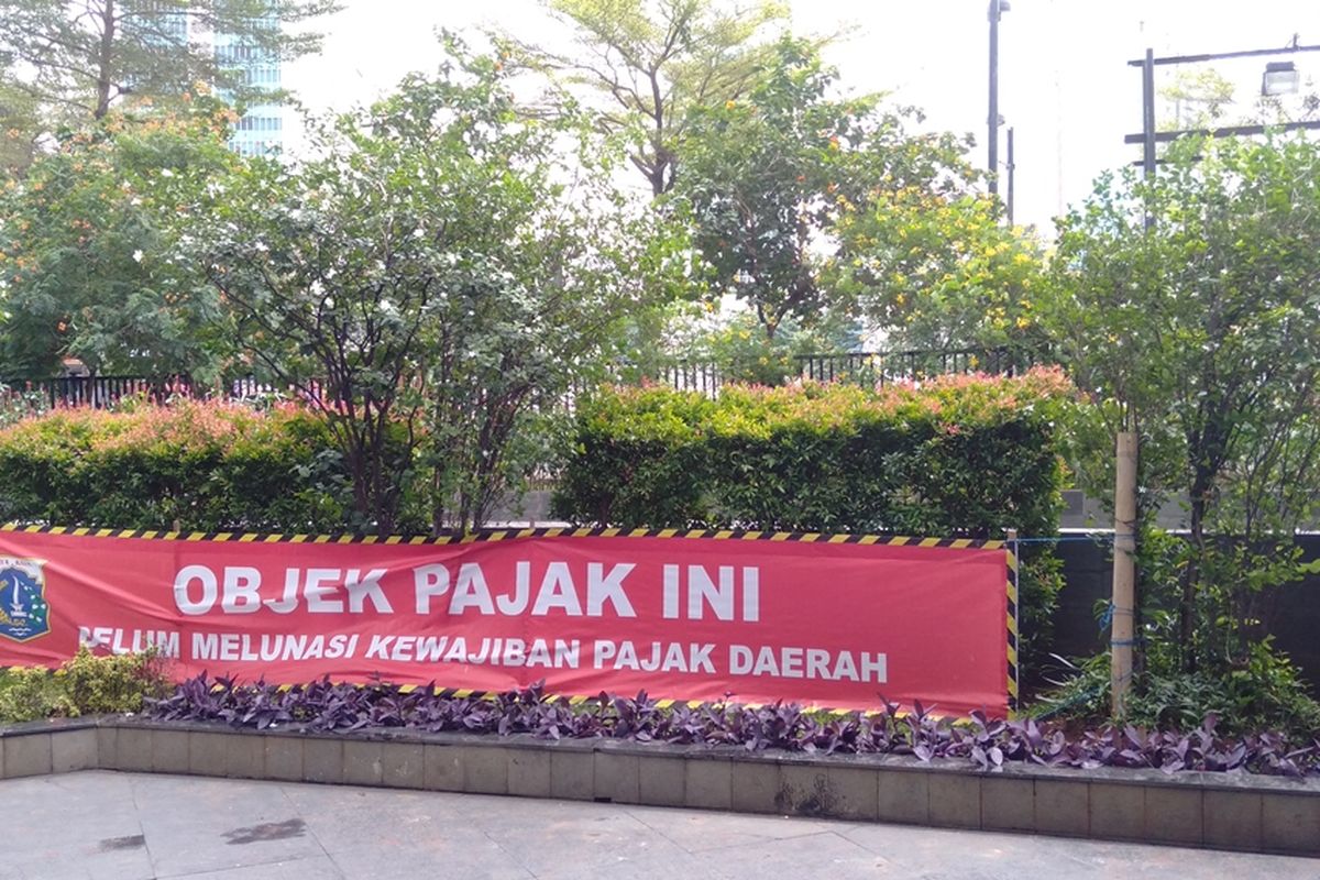 Plang tanda penunggak pajak di halaman gedung The Grove Suites, Kuningan, Jakarta Selatan, Selasa (10/12/2019)