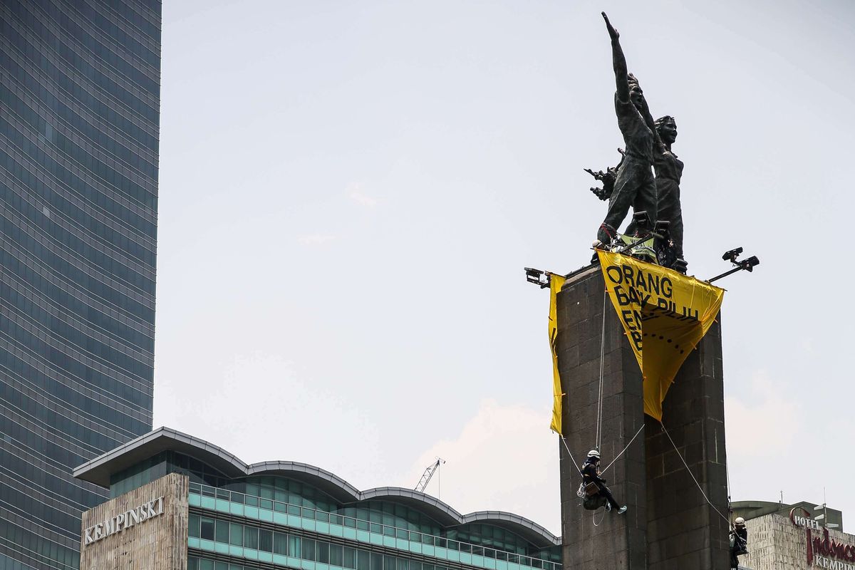 Aktivist dari greenpeace memanjat Monumen Selamat Datang atau patung Bundaran Hotel Indonesia, Jakarta Pusat, Rabu (23/10/2019). Mereka membentangkan spanduk kuning bertuliskan Orang Baik Pilih Energi Baik dan Lawan Perusakan Hutan #ReformasiDikorupsi.