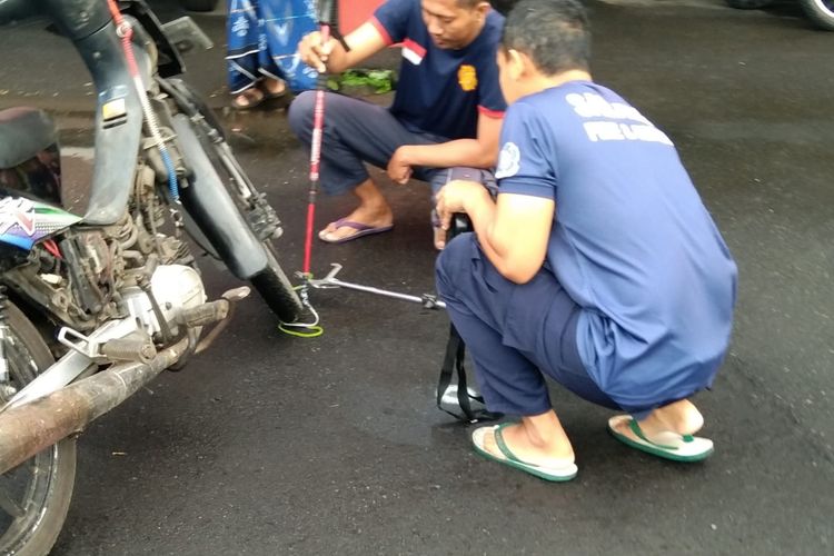 Petugas Damkar Kota Salatiga mengevakuasi ular yang masuk ke sepeda motor.