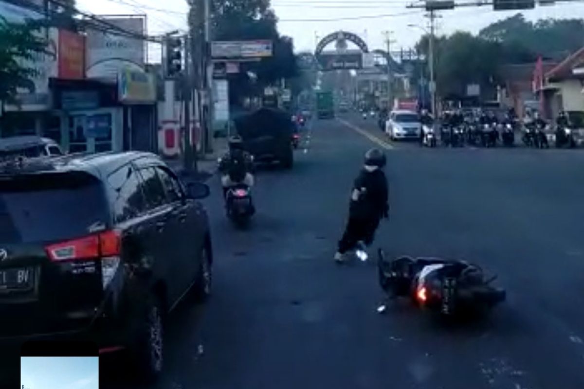 Seorang perempuan meninggalkan sepeda motornya di tengah jalan saat mobil damkar akan lewat