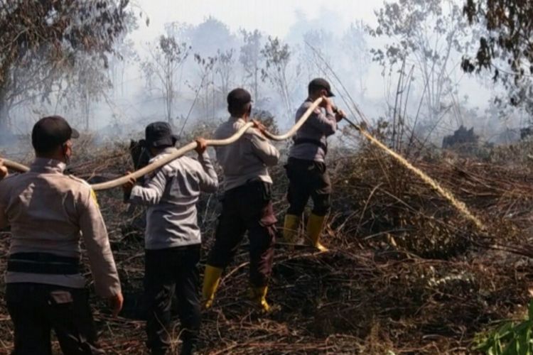 Petugas kepolisian memadamkan titik api karhutla di Kecamatan Bunga Raya, Kabupaten Siak, Riau, Senin (8/3/2021).