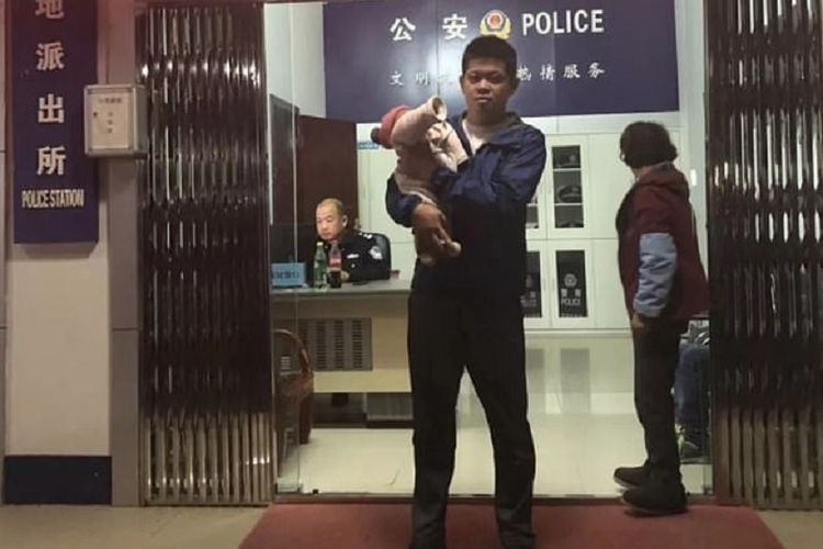 Xiaohui (tengah) berdiri sambil memegang anaknya. Dia ditangkap karena menjual putrinya yang baru berusia 10 hari kepada sepasang suami istri dengan harga Rp 8 juta.