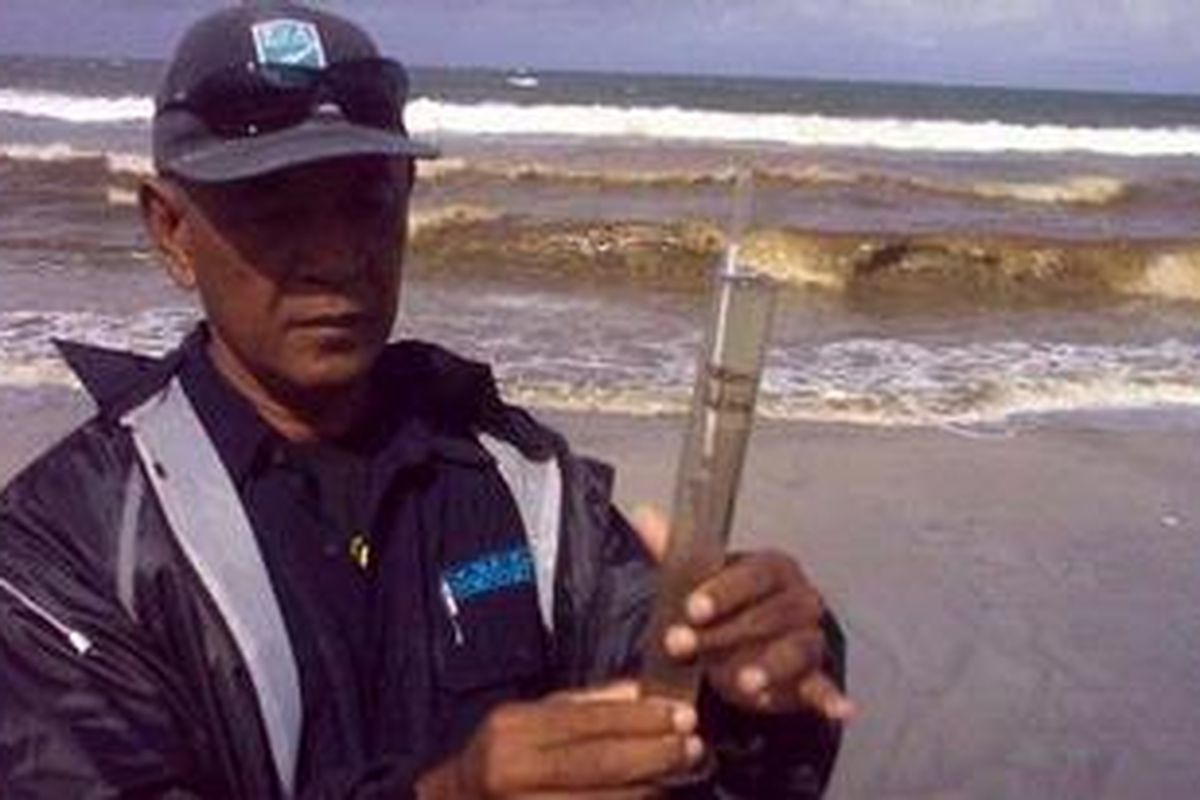 Kepala Satgas Pantai Kuta Anak Agung Ngurah Tresna memeriksa air laut menggunakan Salinometer di Pantai Kuta, Selasa (1/3/2011). Tampak di belakang Ngurah Tresna, warna air pantai Kuta berubah menjadi coklat pekat. 
