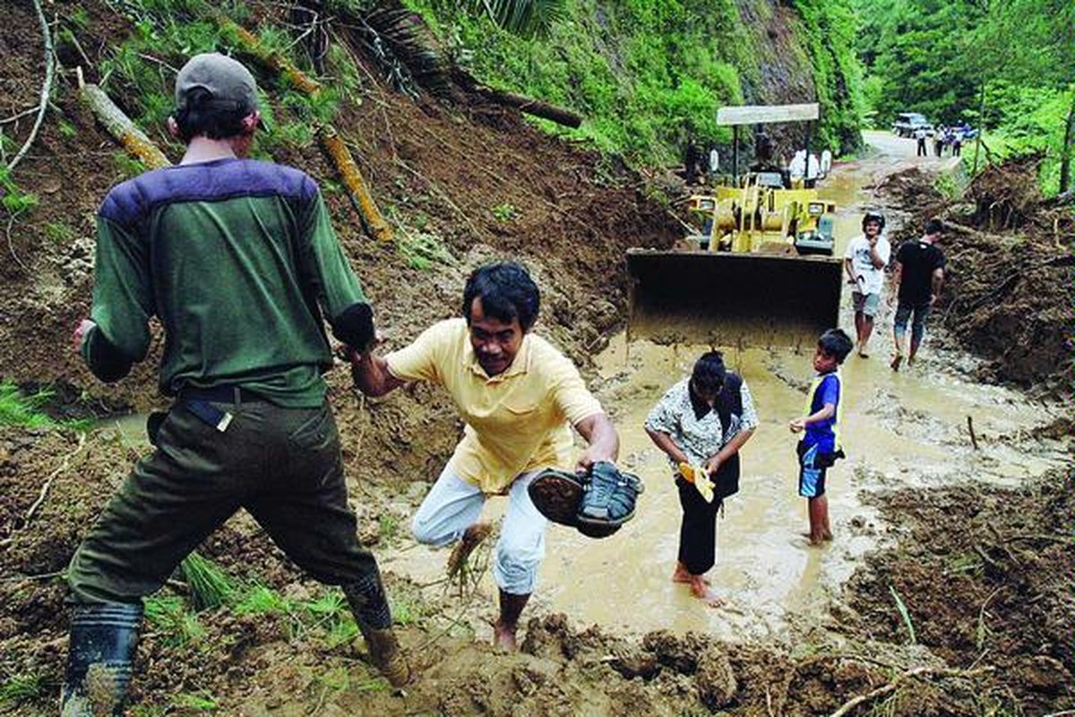 Sejumlah warga berusaha menembus timbunan longsor yang menutup ruas jalan Sempor- Klampok, jalur alternatif yang menghubungkan Kebumen- Banjarnegara, Senin (25/10). Longsor ini merupakan bagian dari serangkaian bencana longsor dan banjir yang menimpa Kebumen, Banyumas, dan Banjarnegara akibat hujan lebat yang terjadi pada hari Minggu (24/10).