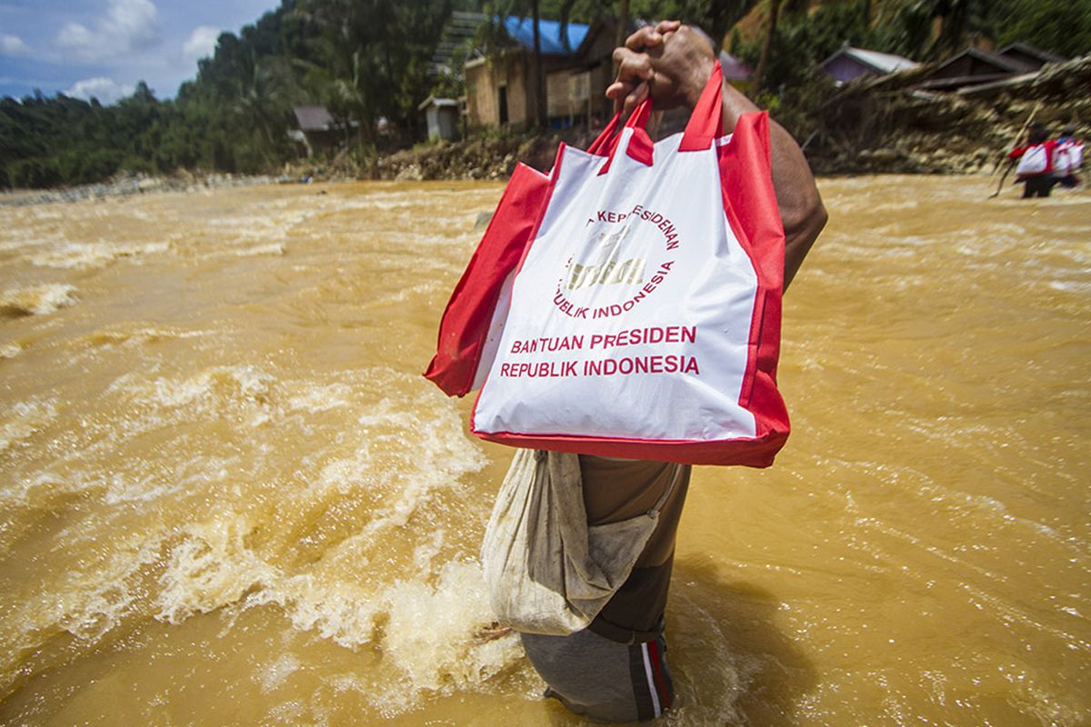 Seorang warga menyeberangi sungai saat memikul paket sembako bantuan Presiden di pedalaman Pegunungan Meratus, Desa Datar Ajab, Kalimantan Selatan. Hujan tiada henti pada Selasa (12/1/2021) berujung petaka dengan meluapnya sungai hampir di seluruh wilayah Kalimantan Selatan, sedikitnya 11 kabupaten/kota porak poranda diterjang banjir termasuk Kota Banjarmasin.