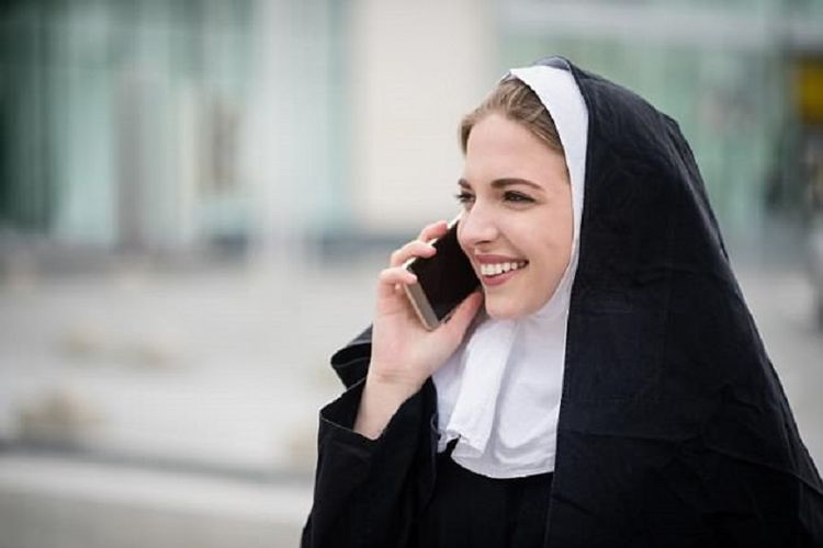 Seorang biarawati sedang menelepon menggunakan ponsel.