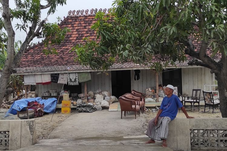 Salah seorang pedagang Pasar Karanganyar Demak, duduk di depan rumah usai membereskan dagangannya yang bercampur lumpur. (KOMPAS.COM/NUR ZAIDI)