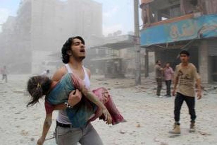 Seorang pria membawa seorang gadis muda yang terluka dalam serangan barel bom oleh pasukan pemerintah, 3 Juni 2014 di kabupaten Kallaseh, Aleppo. Sebanyak 2.000 warga sipil, termasuk lebih dari 500 anak-anak, telah tewas dalam serangan udara rezim di daerah yang dikuasai pemberontak.