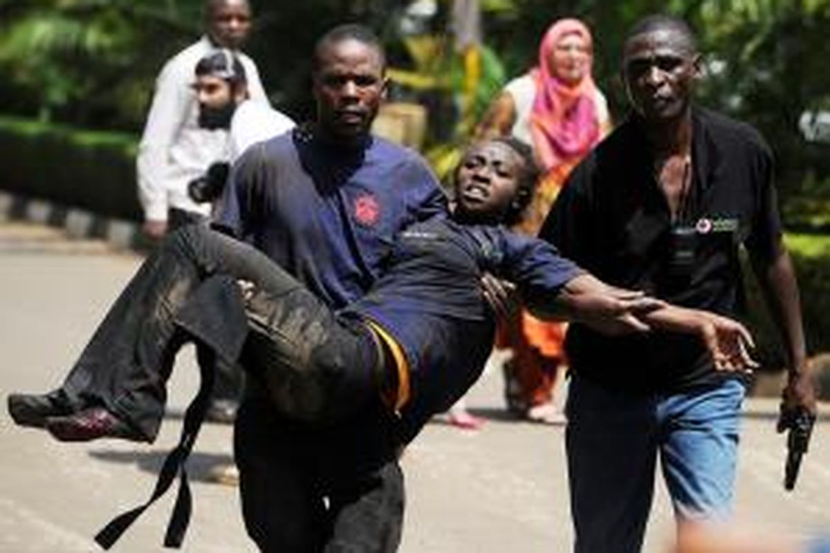 Seorang pria membopong seorang perempuan yang terluka setelah sekelompok orang bersenjata menyerbu sebuah pusat perbelanjaan di Nairobi, Kenya dan menembaki pengunjung.