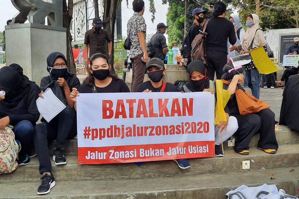 Massa aksi membentangkan poster berisi protes dalam demo tolak PPDB 2020 DKI Jakarta di Taman Ekspresi Monas, Jakarta Pusat, Jumat (3/7/2020).