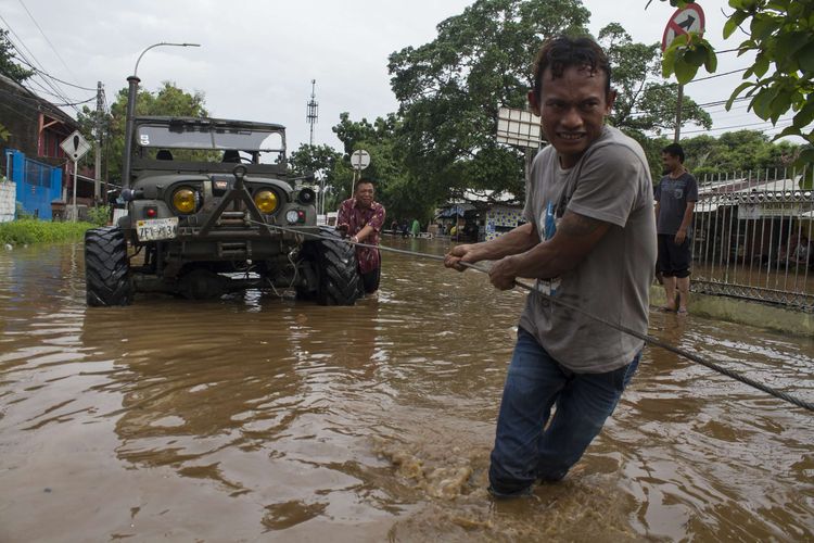 Sejumlah warga mengevakuasi mobil jeep yang terendam banjir di Jl. Raya Pondok Gede, Kramat Jati, Jakarta Timur, Rabu (1/1/2020). Luapan air Kali Baru sebabkan wilayah Kramat Jati terendam hingga sebahu orang dewasa.