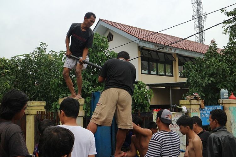 Sejumlah warga bergotong royong membuka pintu air kali Sekretaris, Kebon Jeruk, Jakarta Barat, Rabu (1/1/2020) siang.