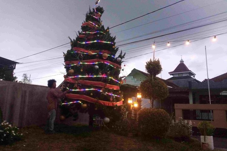 Seorang pemuda menghias pohon natal di halaman rumah Satpo Winasis.