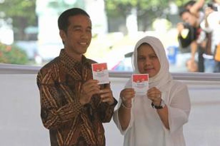 Calon presiden Joko Widodo bersama istrinya Iriana, menunjukkan surat suara usai mencoblos dalam Pilpres 2014 di TPS 18 Menteng, Jakarta Pusat, Rabu (9/7/2014).