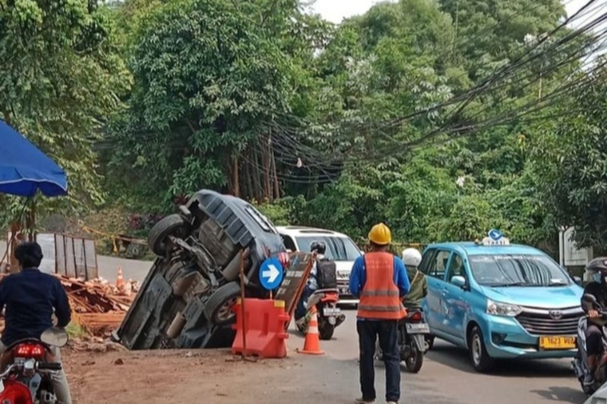 Sebuah mobil terperosok ke dalam lubang di Jalan Margasatwa Raya, Pasar Minggu, Jakarta Selatan, Senin (13/3/2023) 