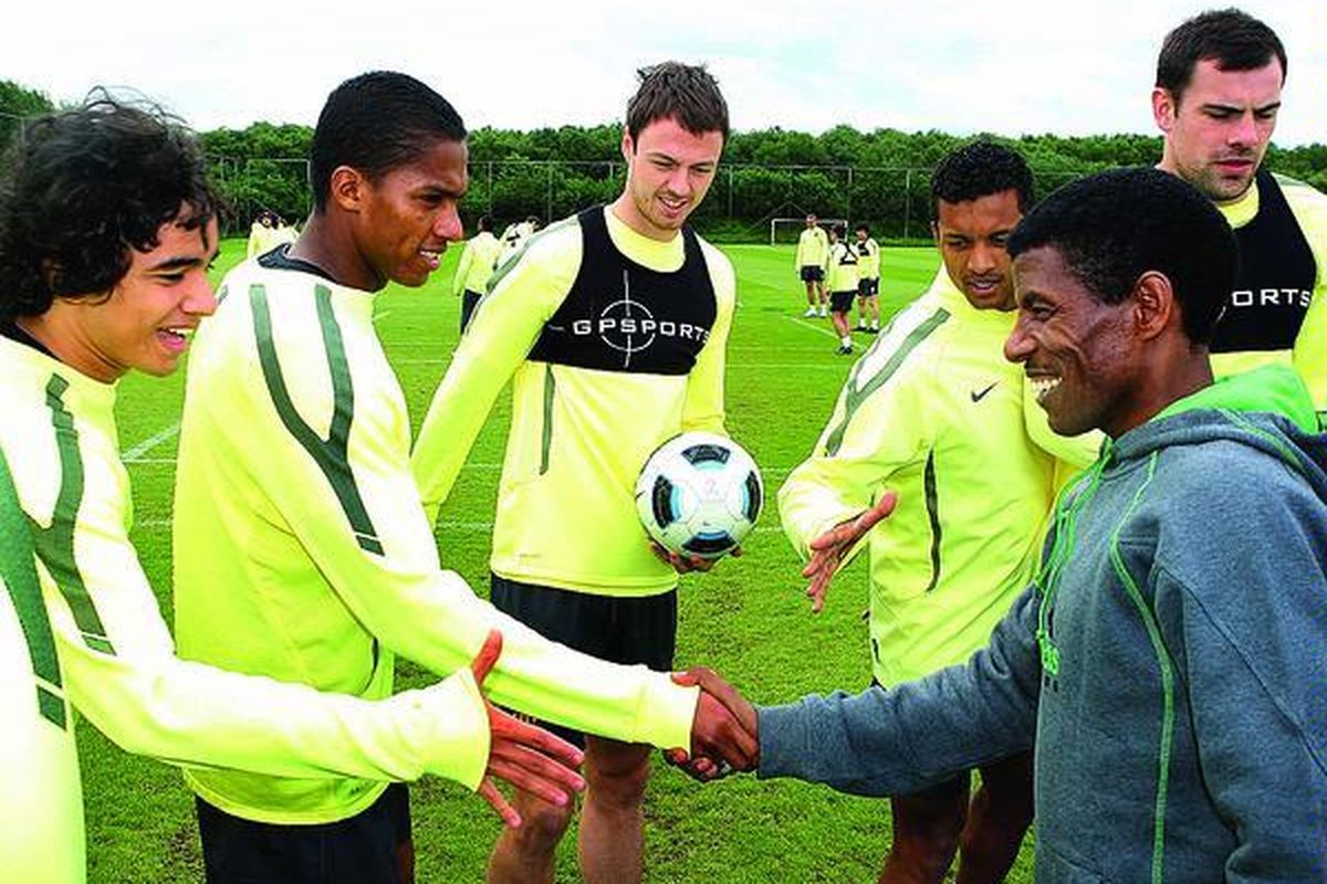 Peraih medali emas Olimpiade nomor 10.000 meter,  Haile Gebrselassie (kanan),  bersalaman dengan pemain Manchester United, Antonio Valencia, di sela-sela latihan tim The Red Devils di Carrington, Manchester, Inggris, Jumat (13/5).