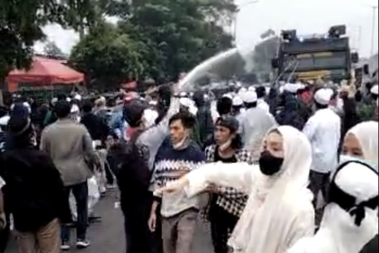 Polisi menyemprot massa diduga simpatisan Rizieq Shihab dengan water cannon di Jalan I Gusti Ngurah Rai dekat Flyover Pondok Kopi, Jakarta Timur pada Kamis (24/6/2021).