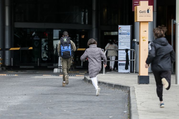 Warga Israel berlarian mencari perlindungan saat sirene serangan udara meraung-raung di Tel Aviv, Sabtu (28/2/2026). Iran melakukan serangan balasan setelah operasi gabungan Amerika Serikat-Israel menghantam Teheran dan enam kota lainnya.