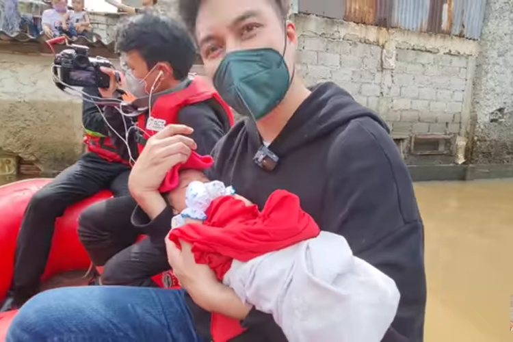 Artis Baim Wong saat membantu mengevakuasi bayi yang terjebak banjir di rumahnya di kawasan Bintaro, Jakarta Selatan.