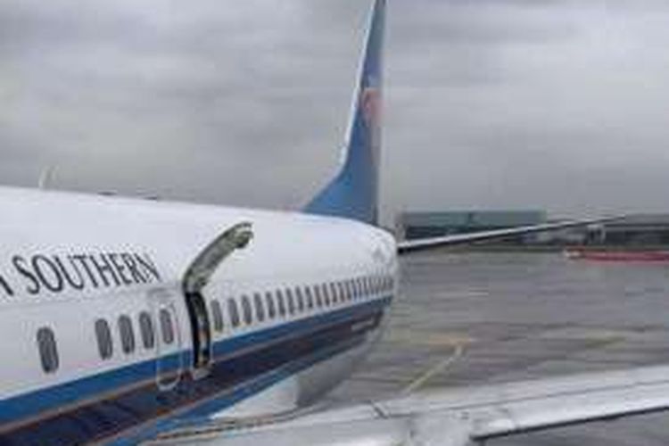 Seorang penumpang membuka pintu darurat pesawat China Southern yang sedang berada di bandara Chengdu, Rabu (9/3/2016).