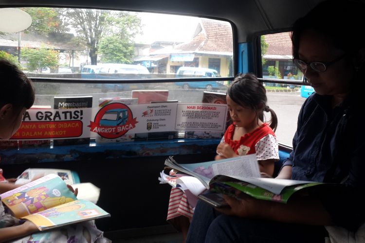 Seorang penumpang dan anak - anak saat baca buku di dalam angkot milik Sugiarto di Terminal Landungsari, Kota Malang, Senin (17/4/2017)