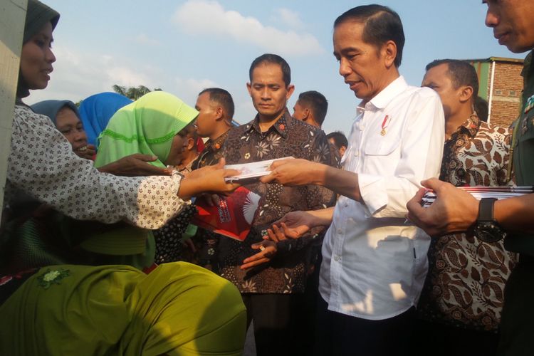 Presiden Joko Widodo sedang membagi-bagikan buku tulis kepada masyarakat Ciamis, Jawa Barat, Sabtu (10/6/2017). Di halaman Kantor Kepala Desa Sindangkasih itu, Jokowi sekaligus meninjau pembagian paket sembako bagi rakyat kecil.