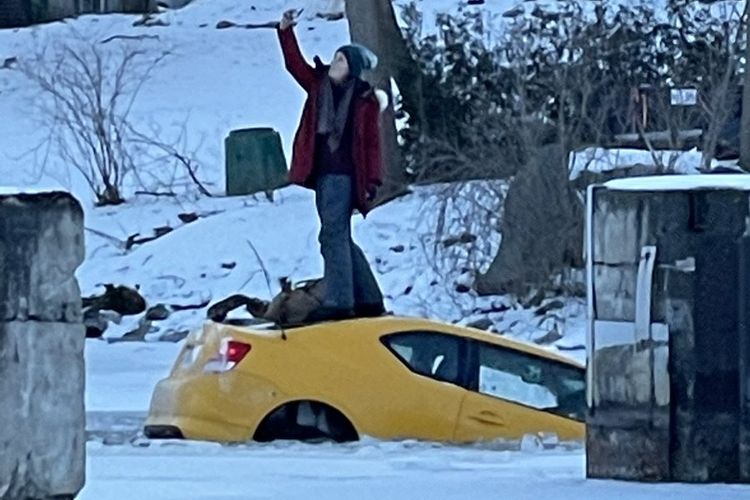 Seorang wanita di Ottawa terlihat mengambil selfie sambil berdiri di atas mobilnya, yang tenggelam ke Sungai Rideau di Manotick.
