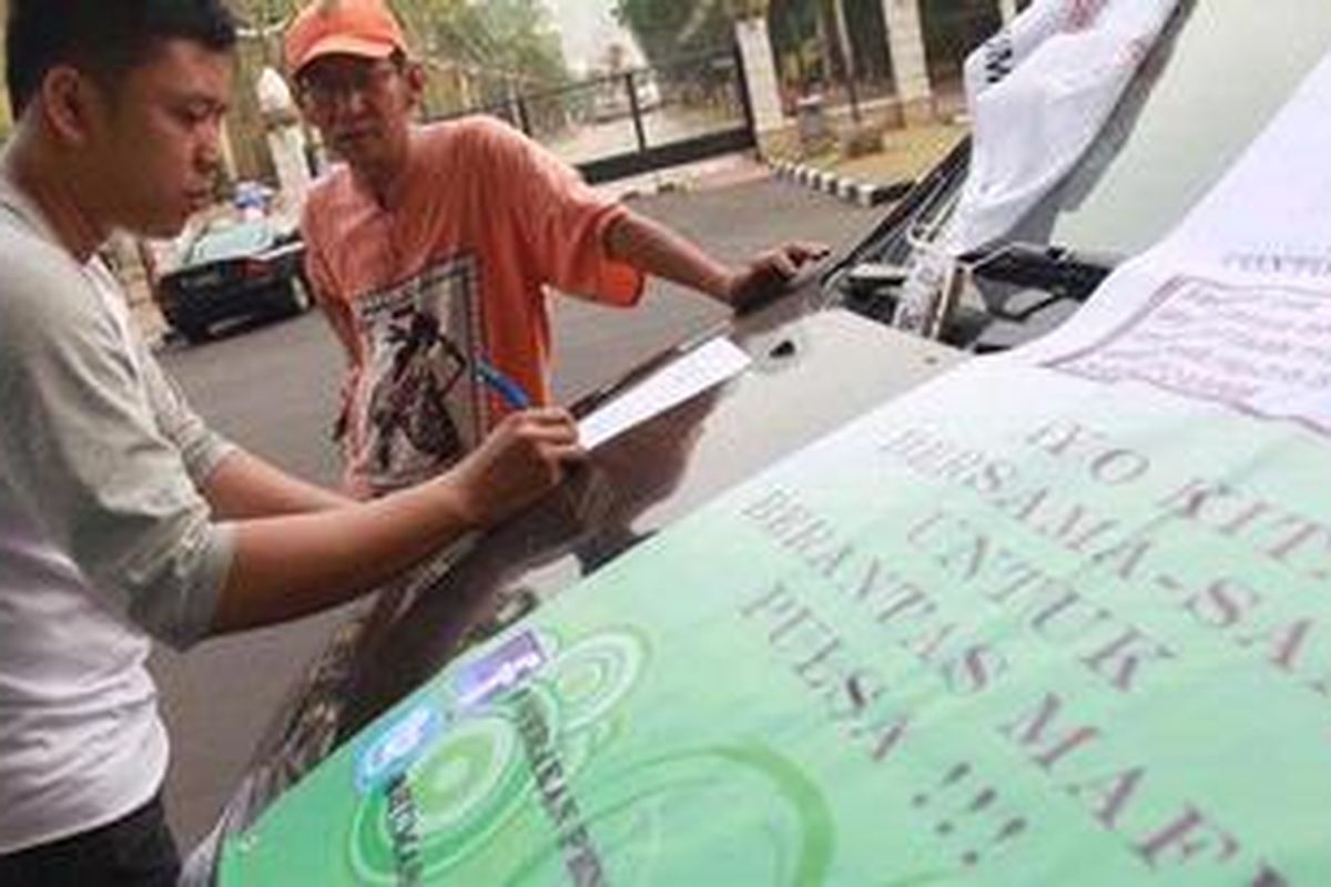 Dani (kiri) dari Lingkar Studi Mahasiswa Jakarta mencatat keluhan warga seputar hilangnya pulsa telepon tanpa sebab saat membuka Posko Keliling Pengaduan Pencurian Pulsa Oleh Operator Telekomunikasi di Gelora Bung Karno, Jakarta Pusat, Minggu (2/10/2011). Dalam dua hari, posko tersebut mengumpulkan ratusan keluhan dari warga pelanggan operator telepon. Nantinya keluhan tersebut diserahkan kepada menteri komunikasi dan informasi. 