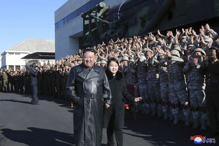 Foto tak bertanggal ini disediakan pada 27 November 2022, oleh pemerintah Korea Utara menunjukkan pemimpin Korea Utara Kim Jong Un, tengah, dan putrinya, kanan tengah, berpose dengan tentara yang terlibat dalam peluncuran Hwasong baru-baru ini.