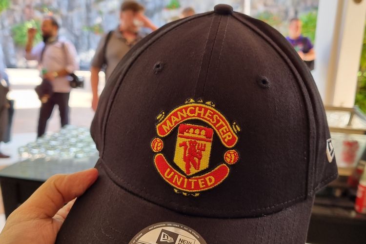 Topi Manchester United yang dibagikan gratis dari Qualcomm.