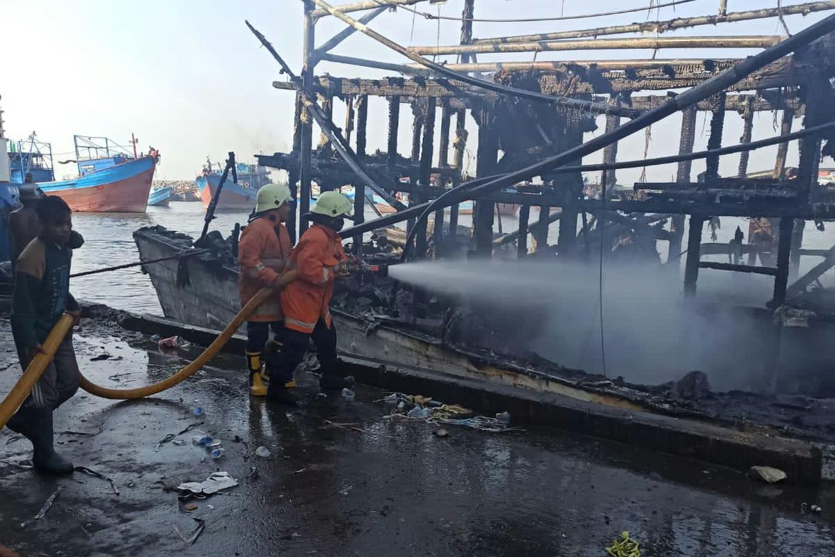 Petugas memadamkan api kapal nelayan yang terbakar di Pelabuhan Muara Baru, Jakarta Utara, Rabu (28/7/2021).