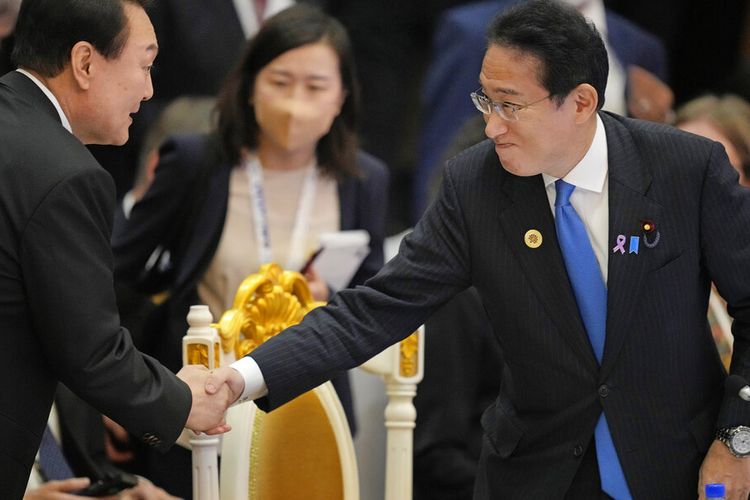 Perdana Menteri Jepang Fumio Kishida, kanan, berjabat tangan dengan Presiden Korea Selatan Yoon Suk Yeol selama KTT ASEAN -Asia Timur di Phnom Penh, Kamboja, Kamboja, Minggu, 13 November 2022. epang akan mewajibkan tes Covid-19 pada setiap pelancong yang datang dari China daratan mulai Jumat (30/12/2022).