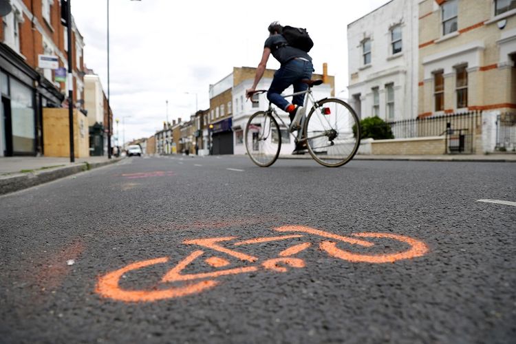 A cyclist cycles by painted stencils on a street to create pop up bike lanes in preparation for distanced bike rides, following the outbreak of the coronavirus disease (COVID-19), London, Britain, May 16, 2020. REUTERS/Peter Nicholls