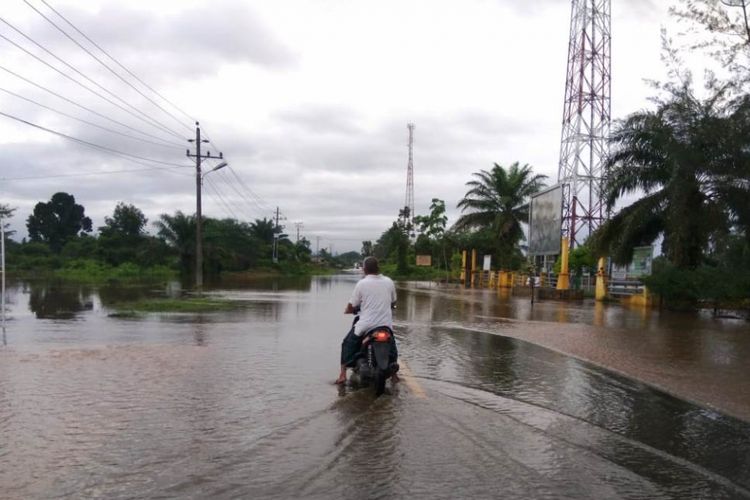 Masyarakat berhenti di jalan nasional yang terendam banjir di Desa Ketapang Indah, Kecamatan Singkil Utara, Kabupaten Aceh Singkil, Sabtu (10/11/2018)