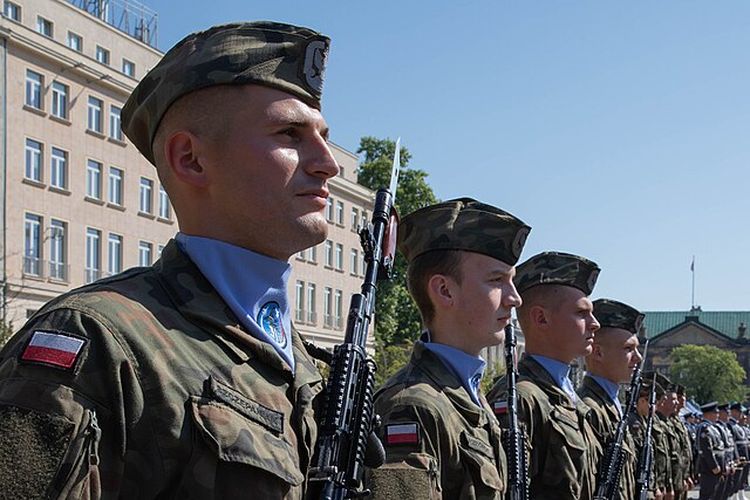 Angkatan Bersenjata Polandia berdiri dalam formasi selama upacara di Poznan, Polandia, 15 Agustus 2023. Ketakutan perang dengan Rusia membuat ribuan warga Polandia ikut pelatihan militer sukarela di perbatasan. Angkanya capai rekor baru pada 2025.