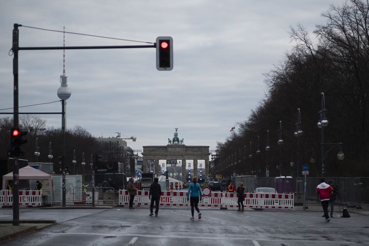 Orang-orang berdiri di depan boulevard Strasse des 17. Juni yang ditutup, pada Malam Tahun Baru di Berlin, Jerman, Kamis (31/12/2020). Lokasi ini biasanya jadi tempat utama perayaan pergantian tahun di Jerman, tapi ditutup seiring masih terjadinya pandemi virus corona.