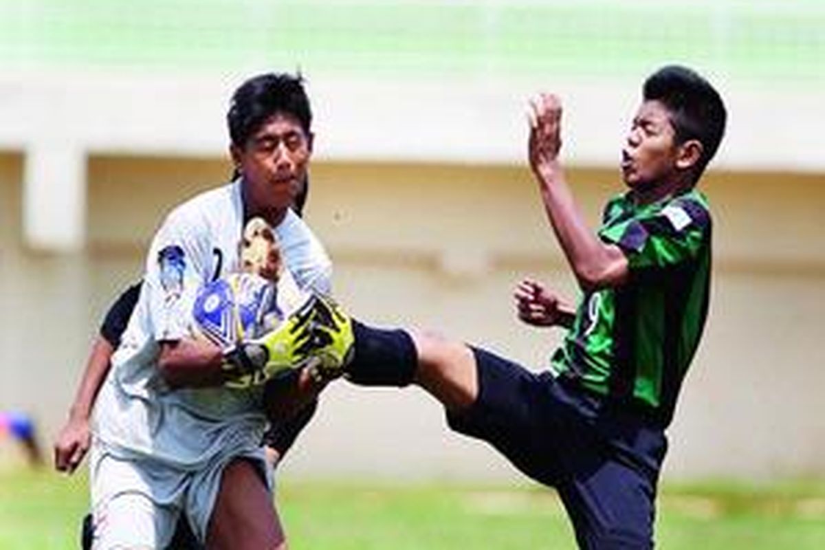 Pemain Sekolah Sepak Bola (SSB) Kabo Mania, Tedi Hasanudin (kanan), berebut bola dengan kiper SSB Villa 2000, Muchammad Alfarisi, saat bertanding pada Liga Kompas Gramedia U-14 di Lapangan GOR Ciracas, Jakarta, Minggu (12/2). Pertandingan berakhir 1-1. (Kompas) 