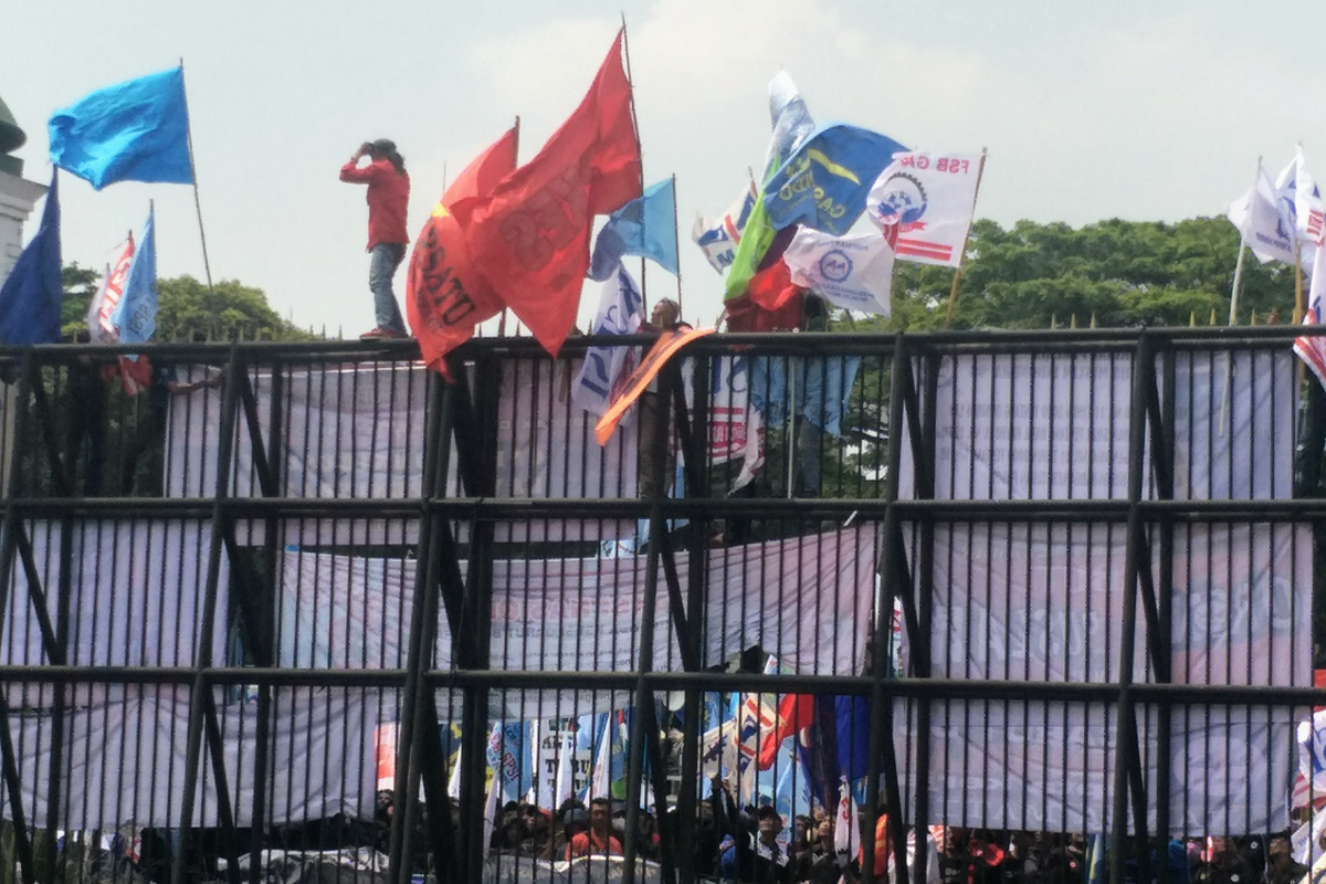 Massa buruh memanjat gerbang utama Gedung DPR/MPR RI, Jakarta Pusat, saat aksi demonstrasi menuntut pencabutan Undang-Undang Cipta Kerja, Rabu (10/8/2022).