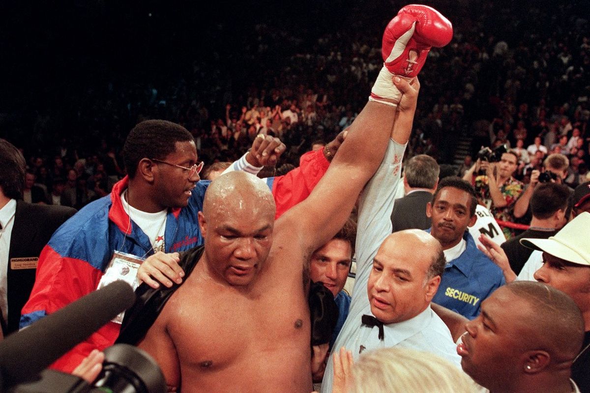 Wasit Joe Cortez (kanan) mengangkat lengan George Foreman setelah Foreman menjatuhkan Michael Moorer di ronde kesepuluh daalam pertarungan gelar kelas berat IBF/WBA pada 5 November 1994 di Las Vegas, Nevada. Mantan juara tinju kelas berat George Foreman, yang bertarung dalam pertempuran ikonik dengan Muhammad Ali sebelum kemudian merebut kembali gelar tersebut dua dekade kemudian, meninggal pada 21 Maret pada usia 76 tahun. (Photo by JOHN GURZINSKI / AFP)