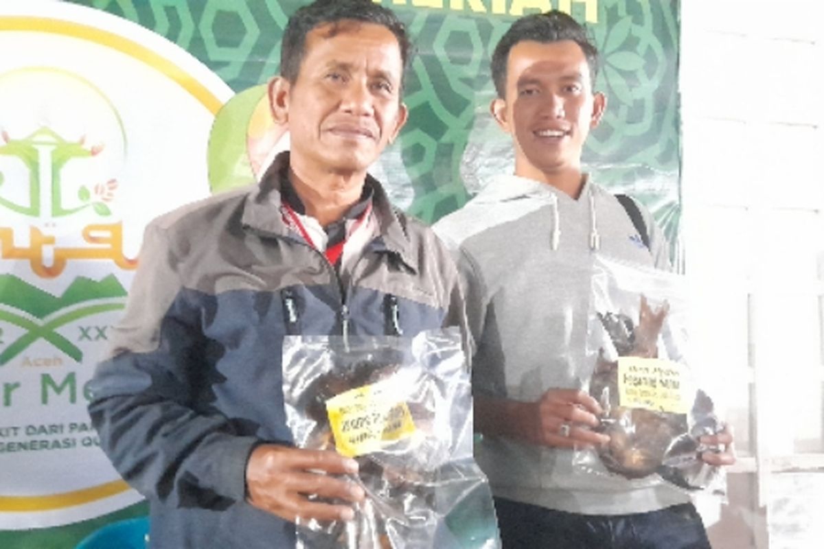 Dua warga Samarkilang, Kecamatan Syiah Utama Aceh sedang memamerkan produk unggulan Samarkilang, Ikan Gegaring disela MTQ XXXV 2022 Aceh, Minggu (19/6/2022) di Lapangan Sengeda, Bener Meriah, Aceh.