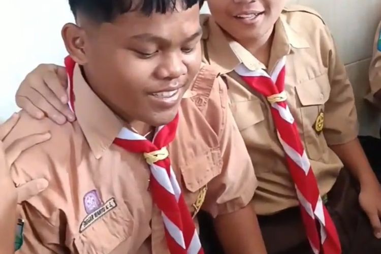 Enggar saat dirangkul temannya dalam momentum pemberian sepatu. Rekan-rekan Enggar di SMK PGRI 1 Kota Kediri, Jawa Timur, patungan dari uang jajann untuk membelikannya sepatu lalu video itu viral.
