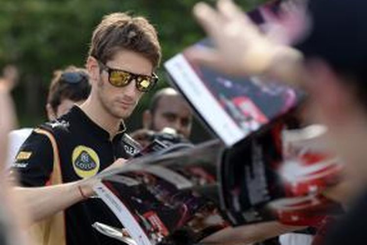 Pebalap Lotus asal Perancis, Romain Grosjean memberikan tanda tangan untuk para penggemar saat tiba di paddock Sirkuit Marina Bay Street, pada sesi latihan bebas tiga GP Singapura, Sabtu (21/9/2013).