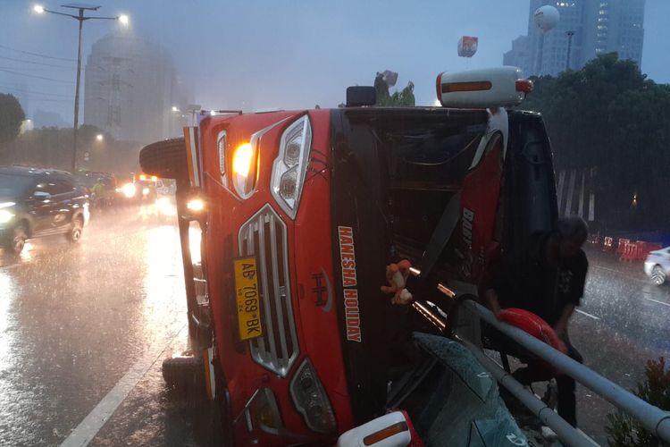 Bus pariwisata menabrak pembatas jalan dan terguling di Jalan Tol Cawang-Grogol, Jakarta, Selasa (7/12/2021) pagi.