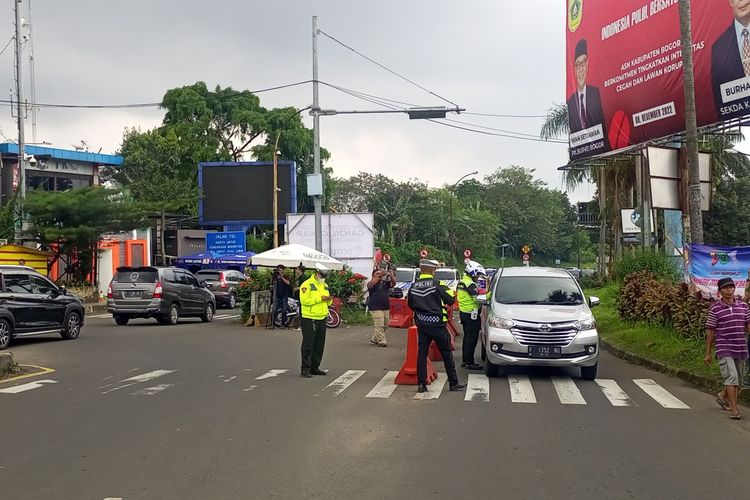 Petugas kepolisian sedang melakukan pengaturan skema ganjil genap di kawasan wisata Puncak Bogor, Jawa Barat.