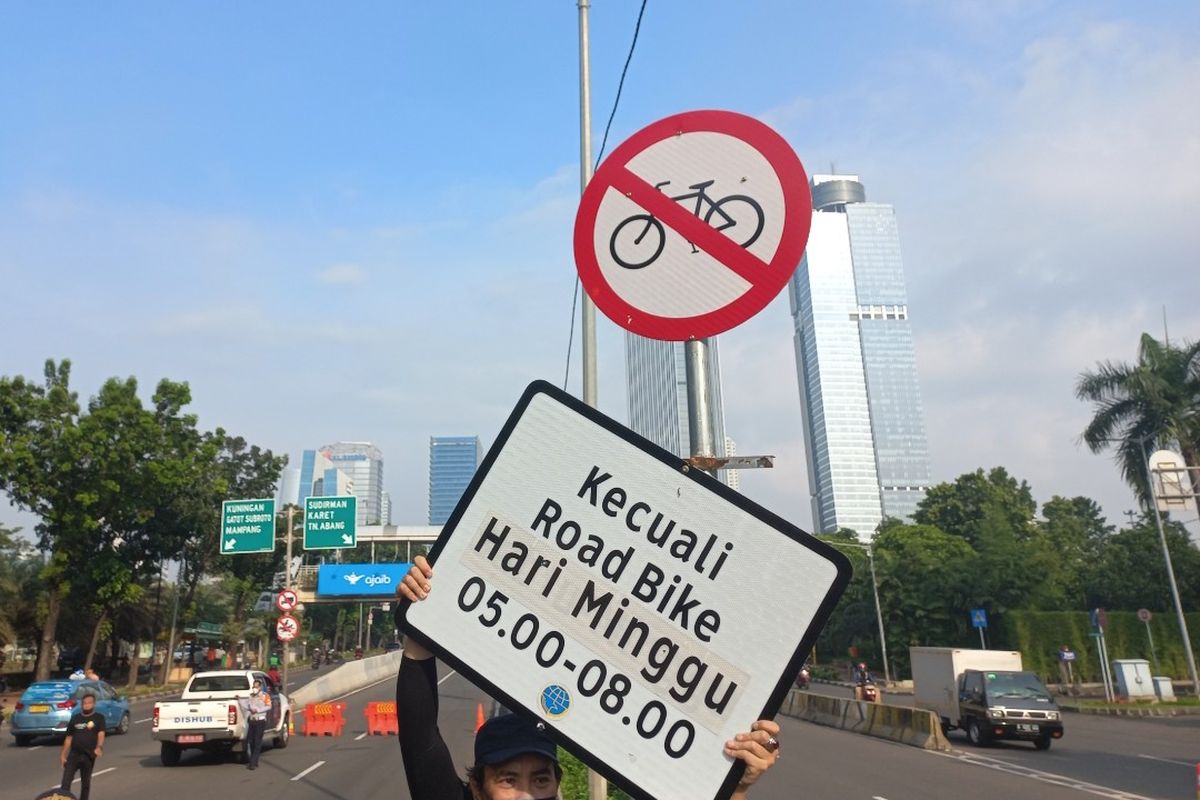 Seorang pesepeda mengangkat papan keterangan rambu uji coba road bike di Jalan Layang Non Tol (JLNT) Casablanca, Jakarta Selatan, Minggu (13/6/2021).