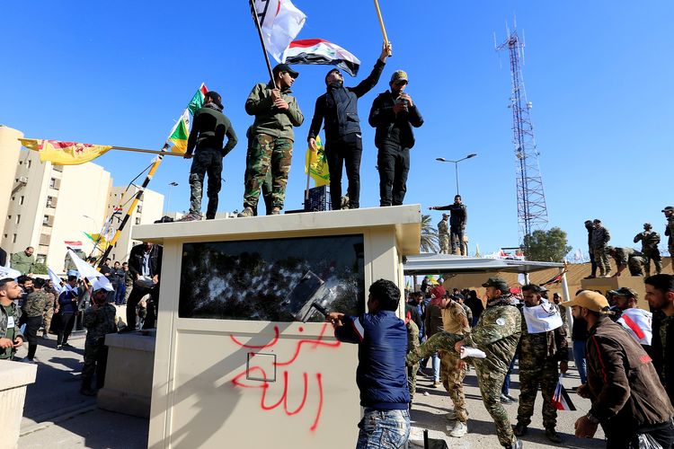 Pengunjuk rasa merusak bilik keamanan di depan Kedutaan Amerika Serikat, saat mereka berkumpul untuk mengutuk serangan udara ke pangkalan milik Hashd al-Shaabi (pasukan paramiliter), di Baghdad, Irak, Selasa (31/12/2019).
