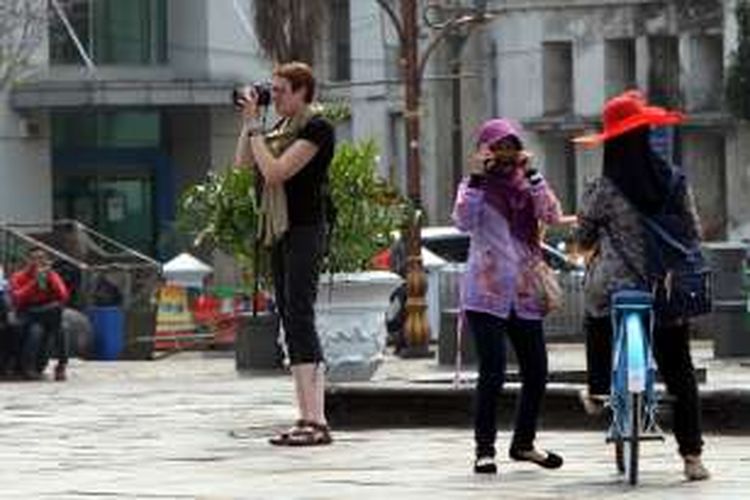 Wisatawan mancanegara (wisman) menikmati suasana di kawasan Kota Tua Jakarta Barat, Kamis (4/9/2014). Jumlah kunjungan wisman ke Indonesia sebanyak 8,8 juta orang atau meningkat 9 persen dibandingkan 2013. Sementara di Singapura, negara berpenduduk 2,7 juta jiwa, kunjungan wisman mencapai 11 juta per tahun. Sektor pariwisata mampu berkontribusi 4 persen dari PDB nasional dengan penerimaan devisa senilai 10 miliar dolar AS atau naik 9,8 persen dibanding 2013. 