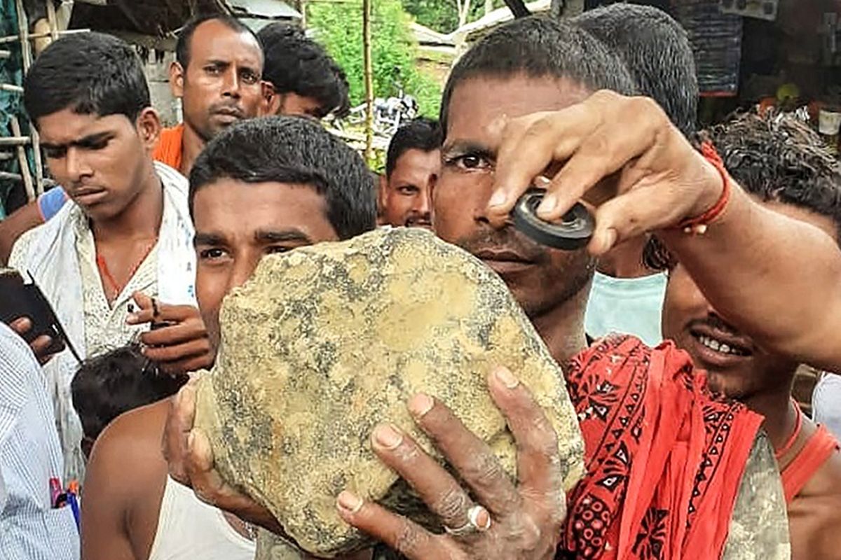 Warga menunjukkan batu seukuran bola sepak yang diduga meteorit yang jatuh di sawah di Bihar, India timur.